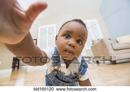 Black baby reaching for camera on living room floor View Large Photo Image Stock Image - Black baby reaching for camera on living room floor. Fotosearch