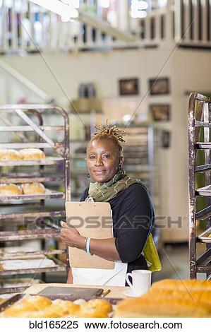 Black baker holding clipboard in bakery kitchen View Large Photo Image Stock Photography - Black baker holding clipboard in bakery kitchen. Fotosearch