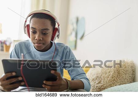 Black boy in headphones using digital tablet View Large Photo Image Stock Photo - Black boy in headphones using digital tablet. Fotosearch