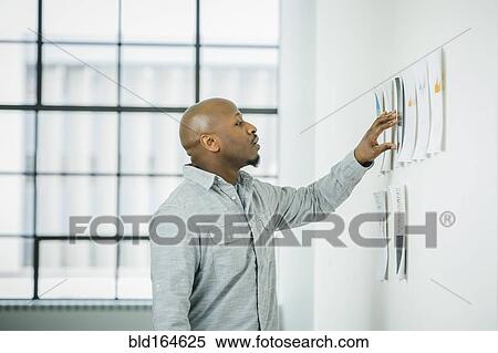 Black businessman examining paperwork on office wall View Large Photo Image Stock Photography - Black businessman examining paperwork on office wall. Fotosearch