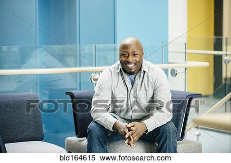 Stock Photography - Black businessman smiling in office lobby. Fotosearch