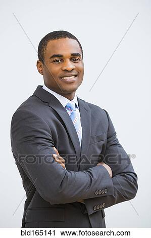Stock Image - Black businessman smiling with arms crossed. Fotosearch