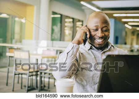 Black businessman talking on cell phone in cafe View Large Photo Image Stock Image - Black businessman talking on cell phone in cafe. Fotosearch