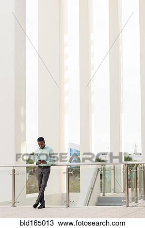 Black businessman using cell phone at railing View Large Photo Image Stock Image - Black businessman using cell phone at railing. Fotosearch