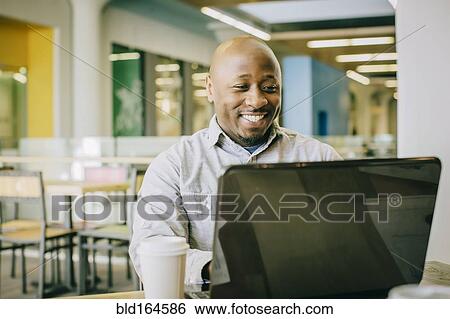 Black businessman using laptop in cafe View Large Photo Image Stock Photograph - Black businessman using laptop in cafe. Fotosearch