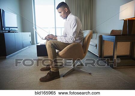 Black businessman using laptop in living room View Large Photo Image Stock Photography - Black businessman using laptop in living room. Fotosearch