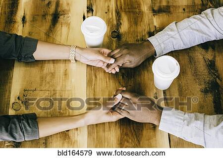 Stock Photo - Black couple holding hands at wooden table, . Fotosearch