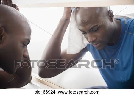Picture - Black man resting near mirror after workout. Fotosearch