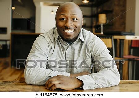 Stock Photography - Black man smiling at counter in cafe. Fotosearch