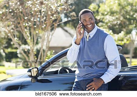 Black man talking on cell phone at convertible View Large Photo Image Stock Photograph - Black man talking on cell phone at convertible. Fotosearch