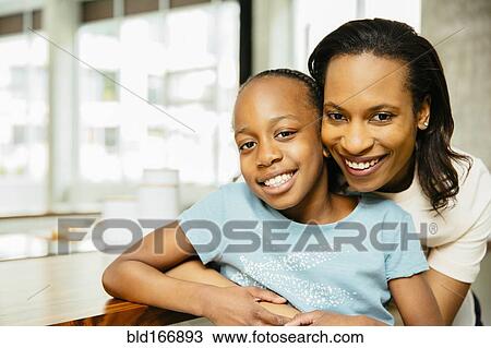 Stock Image - Black mother and daughter hugging. Fotosearch