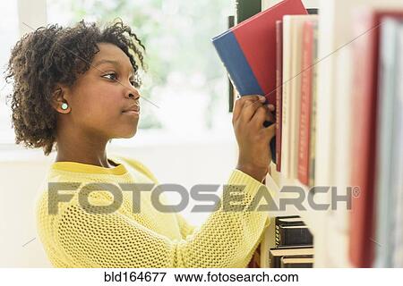 Stock Photo - Black student choosing book from library shelf. Fotosearch