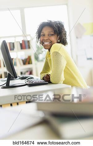 Picture - Black student smiling at computer in classroom. Fotosearch