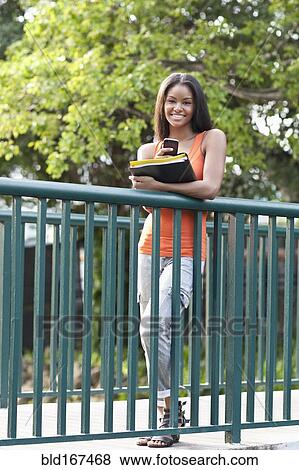Stock Photo - Black student using cell phone on walkway outdoors. Fotosearch