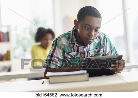 Black student using digital tablet in classroom View Large Photo Image Stock Image - Black student using digital tablet in classroom. Fotosearch