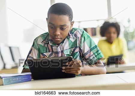 Stock Image - Black student using digital tablet in classroom. Fotosearch