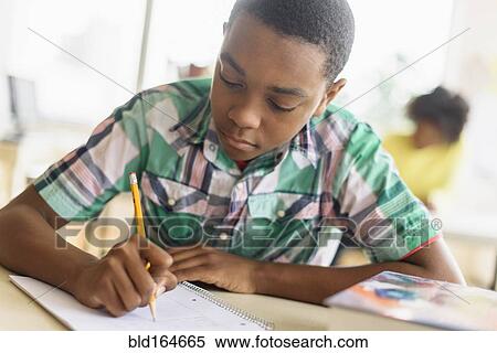 Stock Photography - Black student writing in classroom. Fotosearch