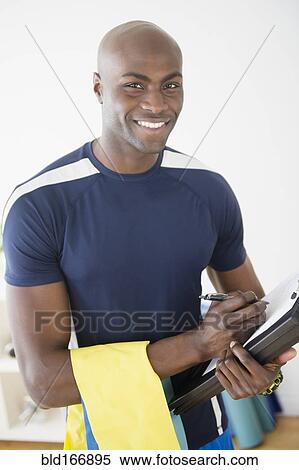 Stock Photography - Black trainer writing notes in yoga studio. Fotosearch