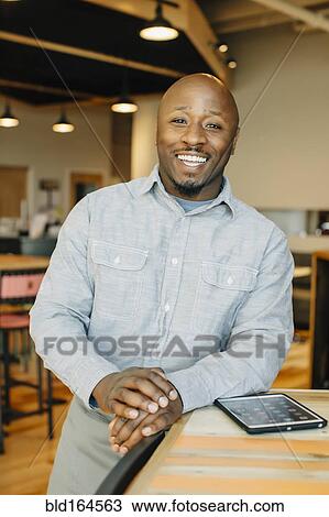 Stock Image - Black waiter using digital tablet in cafe. Fotosearch