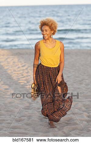 Black woman carrying sandals on beach View Large Photo Image Stock Image - Black woman carrying sandals on beach. Fotosearch