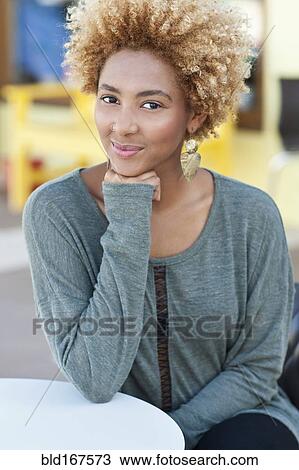 Stock Image - Black woman resting chin in hand outdoors. Fotosearch