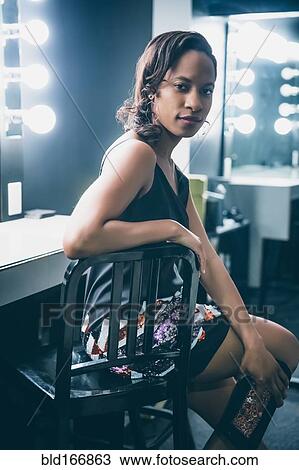 Stock Image - Black woman sitting at vanity mirror. Fotosearch