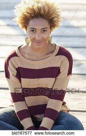Stock Photo - Black woman sitting on wooden boardwalk. Fotosearch