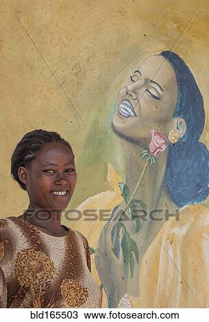 Stock Image - Black woman smiling near mural. Fotosearch