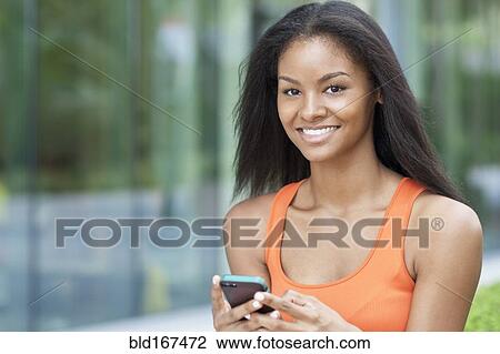 Stock Image - Black woman using cell phone outdoors. Fotosearch