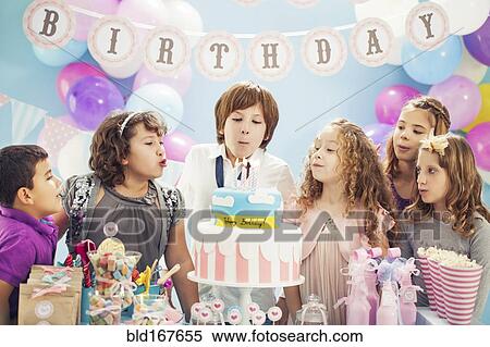 Boy blowing out candles on birthday cake at party View Large Photo Image Stock Photography - Boy blowing out candles on birthday cake at party. Fotosearch