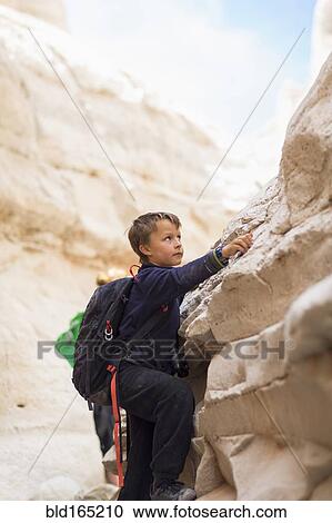 Stock Image - Boy climbing desert rock formations. Fotosearch