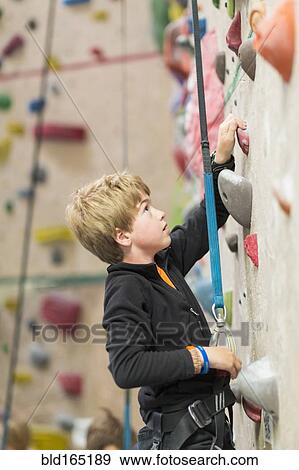 Stock Photo - Boy climbing rock wall indoors. Fotosearch