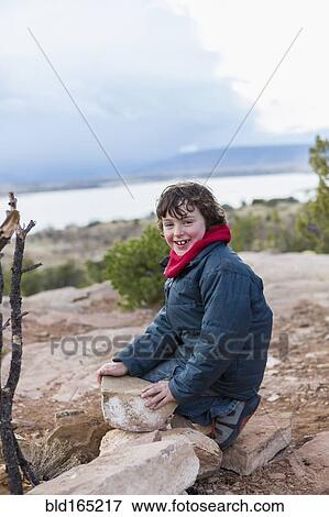 Stock Photo - Boy examining rocks on dirt path. Fotosearch