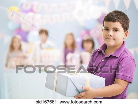 Boy holding wrapped gift at birthday party View Large Photo Image Stock Image - Boy holding wrapped gift at birthday party. Fotosearch