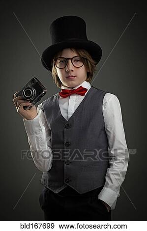 Stock Photo - Boy in top hat photographing with vintage camera. Fotosearch