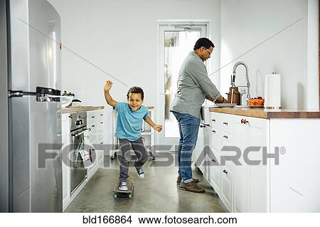 Boy skateboarding near father in kitchen View Large Photo Image Picture - Boy skateboarding near father in kitchen. Fotosearch