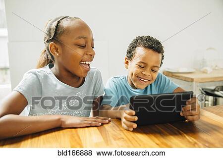Brother and sister using digital tablet in kitchen View Large Photo Image Stock Photo - Brother and sister using digital tablet in kitchen. Fotosearch