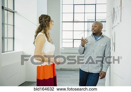 Business people discussing paperwork on office wall View Large Photo Image Stock Image - Business people discussing paperwork on office wall. Fotosearch