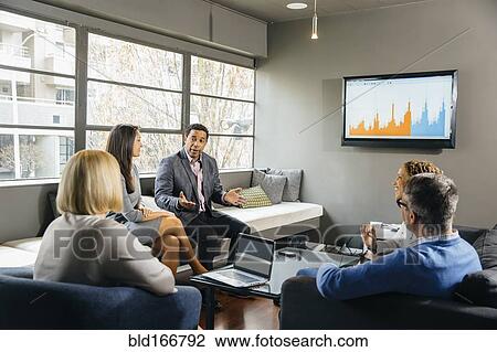 Stock Image - Business people having meeting in office lounge. Fotosearch