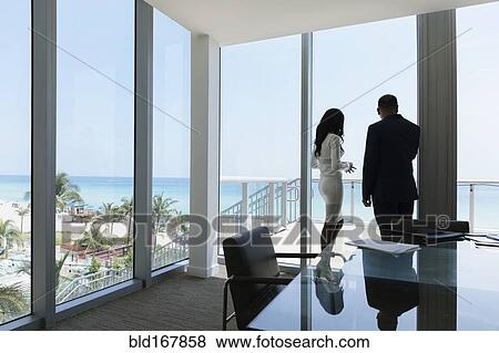 Stock Photo - Business people looking out conference room window. Fotosearch