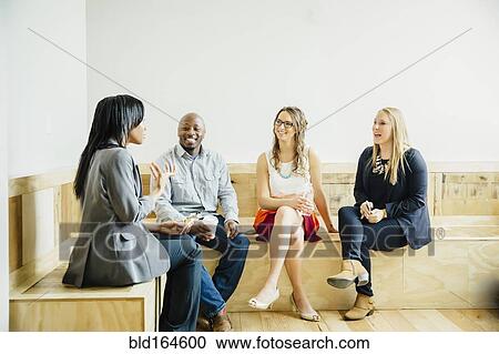 Stock Image - Business people talking in office lobby. Fotosearch