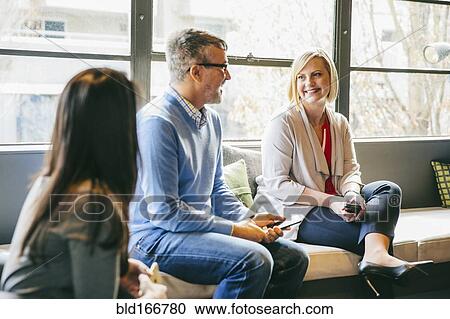 Stock Image - Business people talking in office lobby. Fotosearch