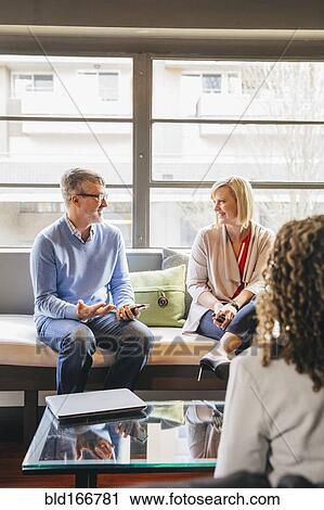 Stock Image - Business people talking in office lobby. Fotosearch