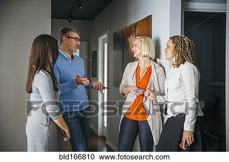 Stock Image - Business people talking in office corridor. Fotosearch