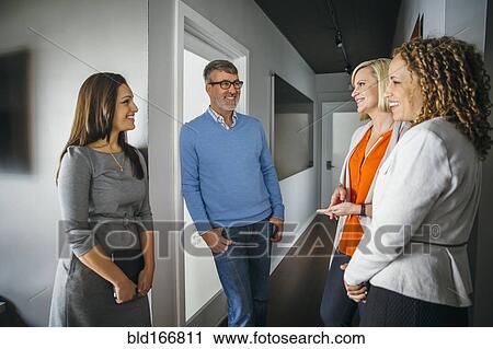 Stock Image - Business people talking in office corridor. Fotosearch