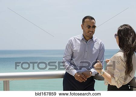 Business people talking on balcony over ocean View Large Photo Image Stock Photo - Business people talking on balcony over ocean. Fotosearch