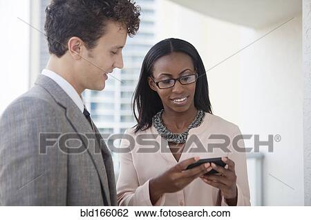 Stock Image - Business people using cell phone in office. Fotosearch