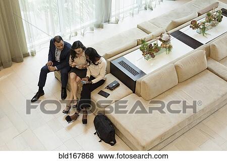 Business people using cell phones in hotel lobby View Large Photo Image Stock Photo - Business people using cell phones in hotel lobby. Fotosearch