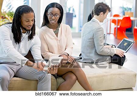 Business people using digital tablet in office lobby View Large Photo Image Stock Photo - Business people using digital tablet in office lobby. Fotosearch