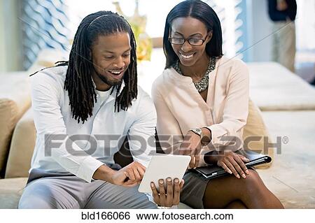 Stock Photograph - Business people using digital tablet in office lobby. Fotosearch